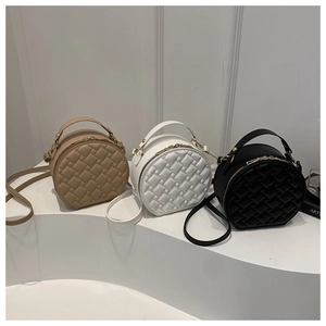 Detailed view of three mini cylinder bags in khaki, white, and black with quilted texture