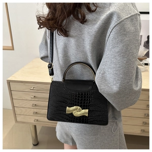 Detail of black crocodile pattern bag with golden wave buckle and metal handle