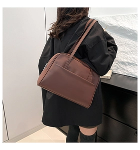 Detail view of large dark brown leather tote bag with front pocket and double straps