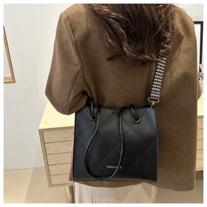 Détail du sac cabas matelassé noir avec large bandoulière pied-de-poule et manteau