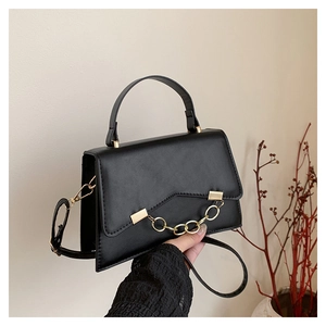 Détail du sac bandoulière noir avec rabat en V et chaîne dorée au design minimaliste