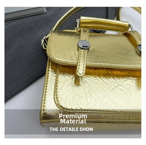 Détail macro de la texture cuir doré froissé et boucle argentée sur sac à bandoulière chic