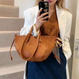 Détail du sac cabas en cuir marron avec un élégant foulard en soie sur l'anse