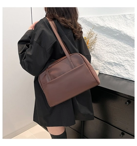 Detail view of large dark brown leather tote bag showing front pocket and matte texture