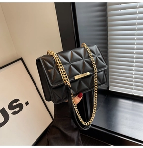 Detail of black quilted leather shoulder bag featuring a gold metal twist lock and chain strap