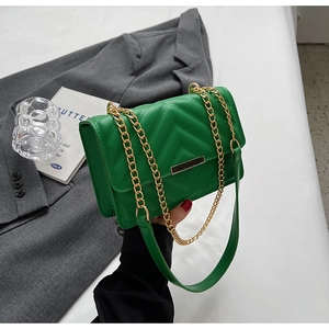 Macro detail of green quilted crossbody bag with gold chain strap and metal lock