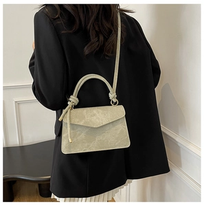 Sage green square handbag with marble texture and knot handle on a model in a blazer