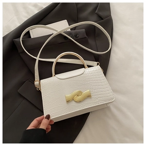 Detail of white crocodile texture leather bag with elegant golden arched metal handle