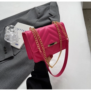 Detail of fuchsia quilted chain bag with V-shaped stitching and gold metal hardware