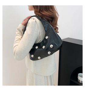 Vue latérale du sac hobo noir avec rivets argentés portés par un mannequin chic