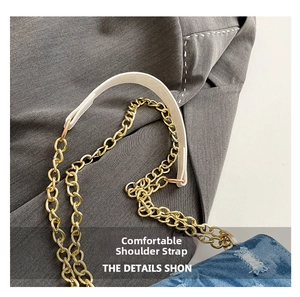 Dettaglio borsa a tracolla in denim blu con catena dorata e comoda tracolla in pelle bianca