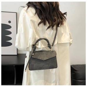 Detail of grey crossbody bag featuring a knotted handle and soft matte suede texture