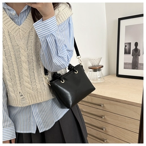 Detail of minimalist black leather crossbody bag with elegant gold metal ring buckle