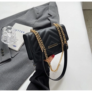 Close-up of black V-quilted leather handbag with golden chain strap and metal lock