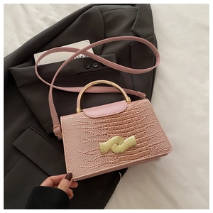 Pink croc-embossed handbag with gold arched handle and wavy lock on white fabric