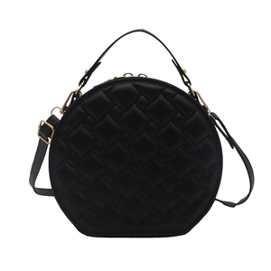 Fashionable black round quilted handbag with gold hardware and shoulder strap on white background