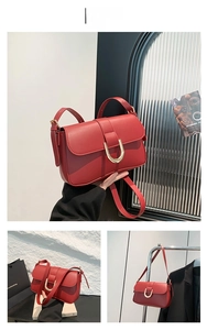 Detail view of red leather crossbody bag featuring a golden U-shaped buckle and side strap