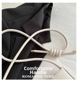 Detail of white leather handbag with knotted strap and gold metal end caps on black suit