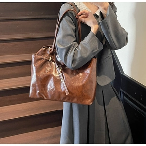 Detail of vintage dark brown tote bag in oil wax leather texture worn with a blazer