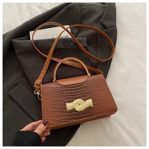 Detail of brown crocodile pattern handbag with golden handle on grey suit jacket