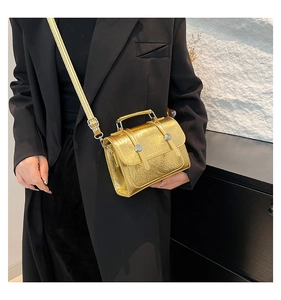 Detail of gold metallic textured crossbody bag showing silver buckle and leather handle