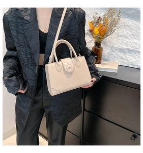 Beige rectangular handbag with crocodile texture accents shown styled on model shoulder