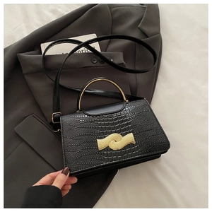 Detail of black crocodile texture bag with gold semi-circle handle and metal wave lock