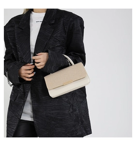 Détail du sac beige avec rabat tissé et fermoir métallique doré de style minimaliste chic