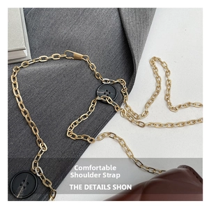 Détail du sac matelassé marron foncé avec bandoulière chaîne dorée et boutons décoratifs