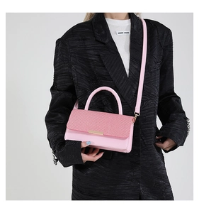 Détail du sac à bandoulière rose avec texture tressée et fermoirs métalliques dorés