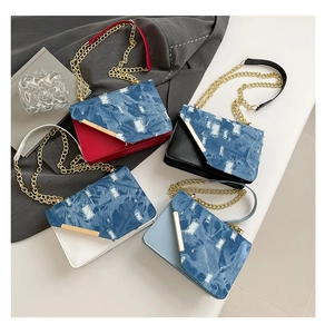 Dettaglio di quattro borse a tracolla in denim patchwork con catena e decori metallo