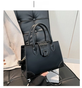 Detail of black crossbody bag featuring smooth and crocodile pattern leather on a chair