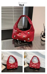 Détail du sac à bandoulière rouge brillant avec clous argentés et poignée plissée