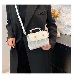 Détail du sac à bandoulière blanc brillant avec boucles en métal et poignée supérieure chic