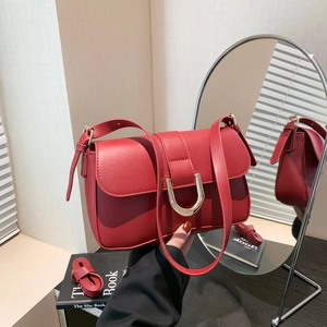 Classic red leather shoulder bag with gold U-shaped buckle in a lifestyle setting