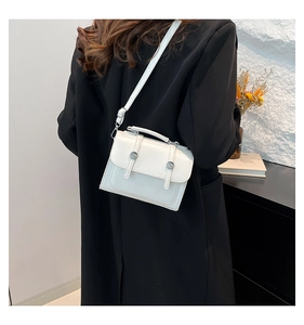 Detail view of retro cream leather crossbody bag styled on a black coat outfit