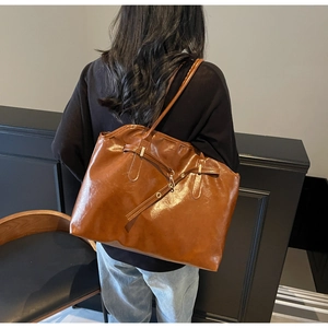 Rear view of a model wearing a large vintage brown faux leather tote bag with straps