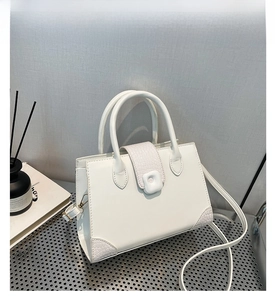 Detail of white square handbag showing crocodile texture leather and metal buckle