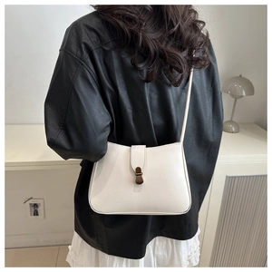 Detail of a vintage off-white shoulder bag on model showing its size and chic retro style