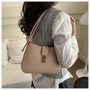 Detail of beige baguette bag with bronze buckle and stylish knotted shoulder strap