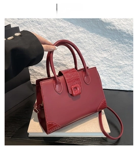 Close-up of red tote bag featuring embossed crocodile pattern and sleek shoulder strap