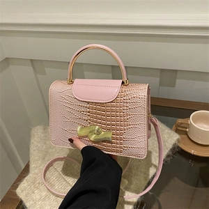 Pink crocodile pattern handbag with gold handle in a stylish lifestyle setting