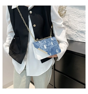 Dettaglio in denim blu strappato e patchwork in pelle bianca su borsa a tracolla