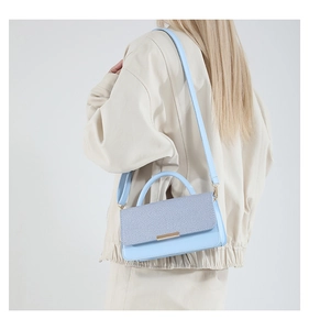 Sac bandoulière bleu ciel élégant avec rabat tressé présenté sur le dos du mannequin