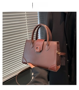 Detail of a brown crossbody bag with crocodile texture trim and top handle in a lifestyle setting