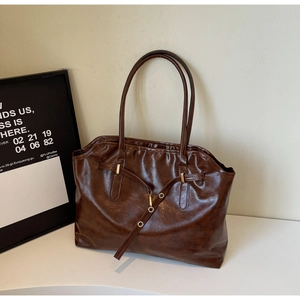 Detail of dark brown vintage faux leather tote with metal buckle and long shoulder straps