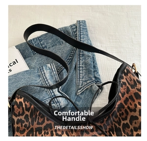 Dettaglio della borsa tote leopardata con cinturini in pelle nera su sfondo di jeans