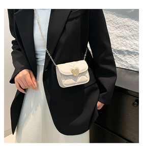 Close-up of quilted cream mini bag with gold heart clasp and elegant metal chain strap