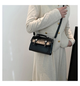 Detail of black wrinkled patent leather shoulder bag with vintage silver metal buttons