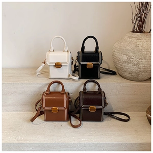 Multiple colors of vintage square handbags with gold buckles on a stone display